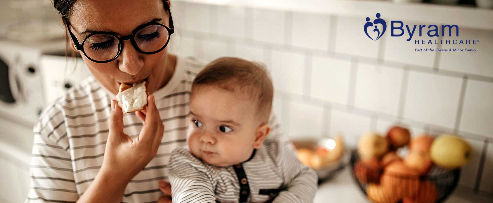 Mom holding baby and eating food.