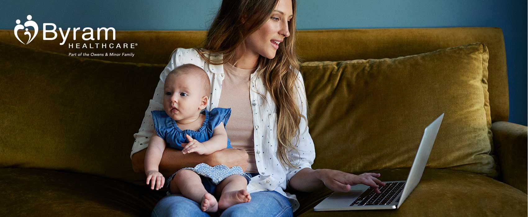Una mamá con su bebé, mirando su laptop.