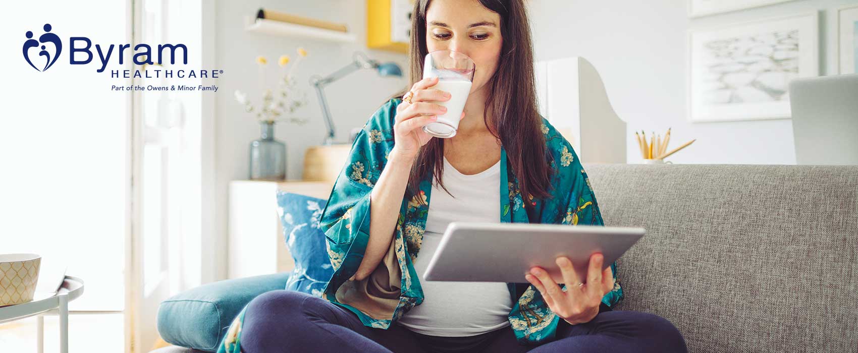 Woman drinking milk and looking at her tablet.