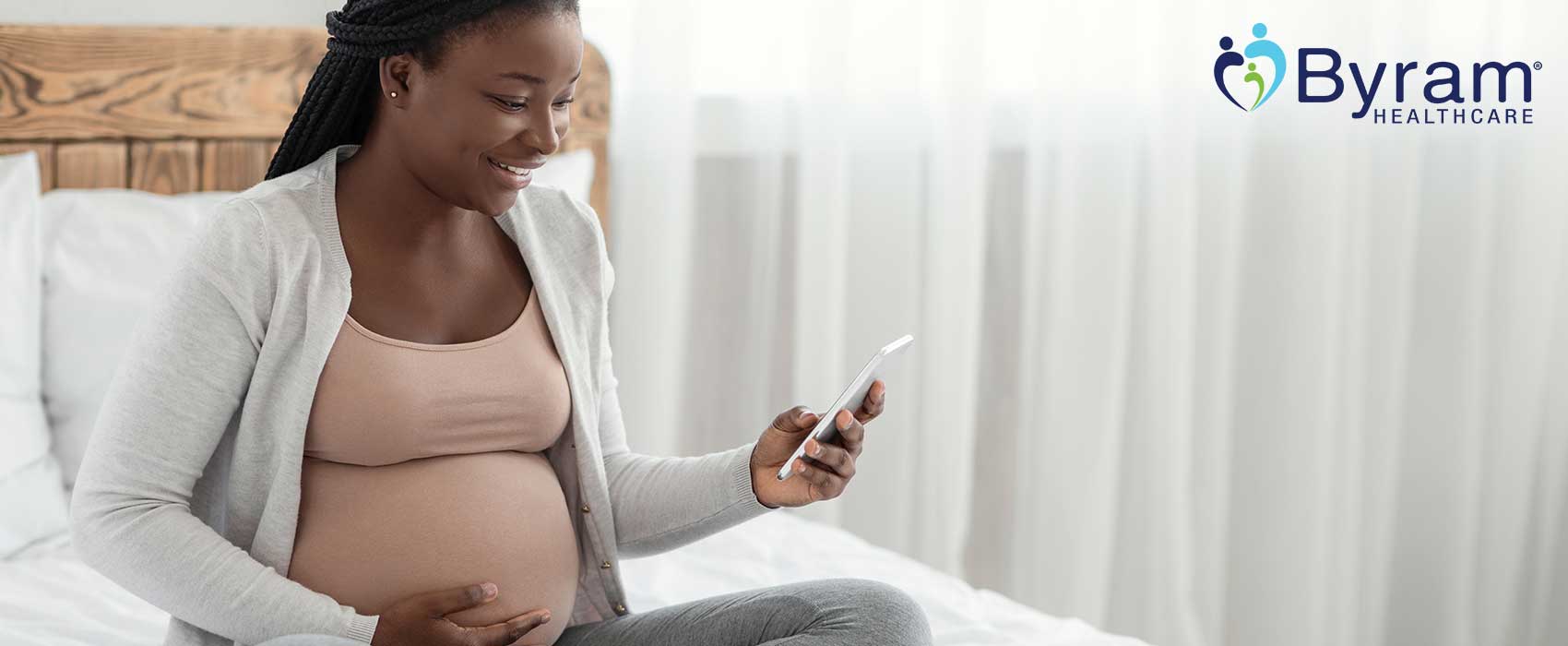 Pregnant lady looking at her phone, smiling.