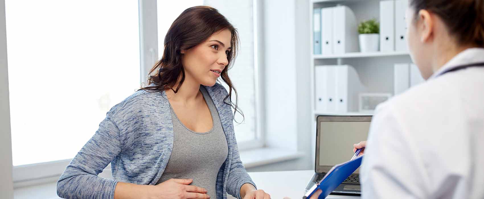 Pregnant woman discussing pelvic organ prolapse with doctor.